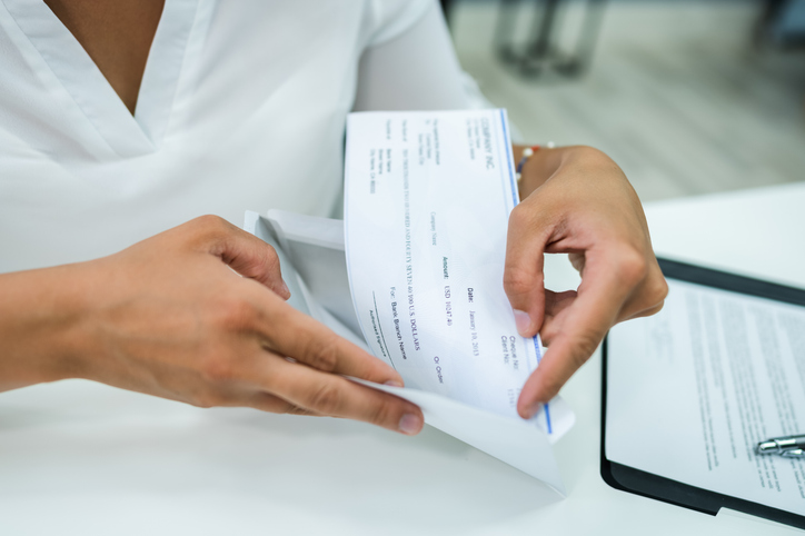 woman opening envelope with paycheck -can creditors take my personal injury settlement?