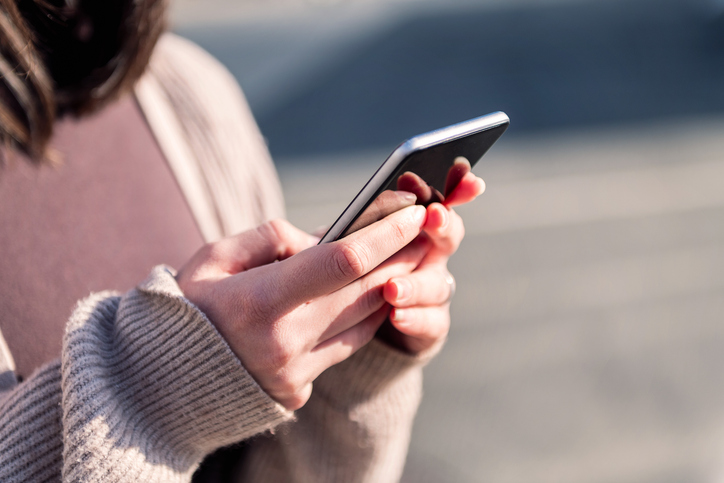 Woman using her phone to post on social media - how social media can destroy your personal injury claim