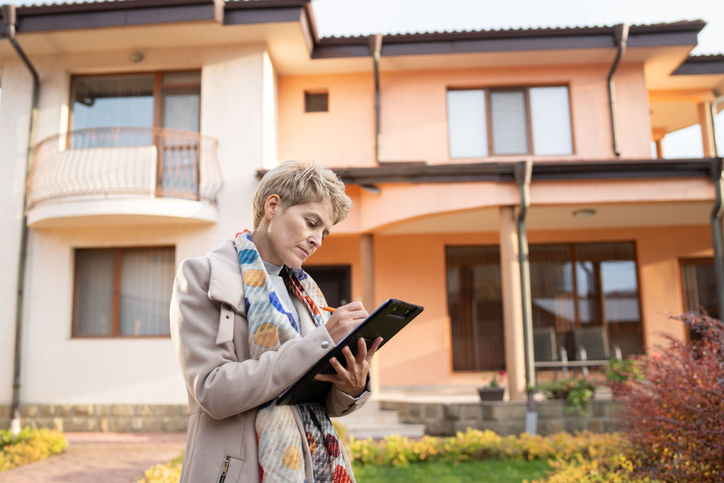 Woman taking notes in front of an apartment complex - Can I sue my landlord for personal injury?