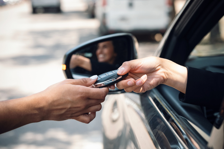 rental company employee handing key to car renter - what happens if you crash a rental car?